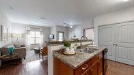 Located at 2150 Katy Fort Bend County Rd in Katy, TX, this single-floor residence offers a thoughtfully designed layout with an open-concept living and kitchen area at its heart. The kitchen is outfitted with warm medium-tone wood cabinetry, granite-style countertops, a double-basin sink, and black appliances including a range, microwave, and refrigerator. A peninsula with bar seating provides both additional prep space and a casual dining option, connecting seamlessly to the dining and living areas. The living room features durable hardwood-style flooring, multiple windows that invite ample natural light, and direct access to an outdoor area via a glass door. The bedrooms are carpeted for comfort and feature neutral tones, large windows with blinds and curtains, and ceiling fans. Each room offers a calm, restful ambiance with generous space. The bathrooms are finished with matching wood cabinetry, granite-style countertops, large mirrors, hardwood-style flooring, and full tub-shower combinations. Additional storage is available via overhead cabinetry. The consistent use of warm wood tones, neutral wall colors, and coordinated finishes throughout creates a cohesive and inviting atmosphere across the entire residence.