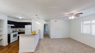 This well-appointed 2-bedroom, 2-bathroom single-story home in Houston, TX offers a thoughtfully designed layout that balances comfort and functionality. The open-concept living and dining area is bright and airy, with plush carpeting underfoot and a ceiling fan overhead. A stone-tiled wood-burning fireplace serves as a standout focal point in the living room, complemented by large windows that invite natural light and provide views to the outdoors.

The kitchen is equipped with dark espresso cabinetry, granite-style countertops, white appliances including a range and refrigerator, and a double basin sink. A breakfast bar with pendant lighting connects the kitchen to the living area, creating an ideal space for casual dining or entertaining. Built-in open shelving adds convenient storage nearby.

Both bedrooms are carpeted and include ceiling fans and windows with blinds, providing comfortable, naturally lit retreats. The bathrooms feature granite-topped vanities with dark wood cabinetry, large framed mirrors, and tub-shower combinations with ample shelf storage. Hardwood-style flooring extends through the kitchen and entry areas, adding warmth and visual contrast throughout the home.