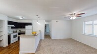 This well-appointed 2-bedroom, 2-bathroom single-story home in Houston, TX offers a thoughtfully designed layout that balances comfort and functionality. The open-concept living and dining area is bright and airy, with plush carpeting underfoot and a ceiling fan overhead. A stone-tiled wood-burning fireplace serves as a standout focal point in the living room, complemented by large windows that invite natural light and provide views to the outdoors.

The kitchen is equipped with dark espresso cabinetry, granite-style countertops, white appliances including a range and refrigerator, and a double basin sink. A breakfast bar with pendant lighting connects the kitchen to the living area, creating an ideal space for casual dining or entertaining. Built-in open shelving adds convenient storage nearby.

Both bedrooms are carpeted and include ceiling fans and windows with blinds, providing comfortable, naturally lit retreats. The bathrooms feature granite-topped vanities with dark wood cabinetry, large framed mirrors, and tub-shower combinations with ample shelf storage. Hardwood-style flooring extends through the kitchen and entry areas, adding warmth and visual contrast throughout the home.
