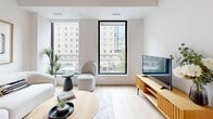 Located on the prestigious Rue Sherbrooke Ouest in Montréal, this thoughtfully designed one-bedroom, one-bathroom unit offers a clean, modern aesthetic throughout. The open-concept kitchen and living area serves as the heart of the home, anchored by a sleek white kitchen featuring flat-panel cabinetry reaching to the ceiling, quartz countertops, stainless steel appliances, a matte black faucet, and a central island with built-in shelving and bar seating — ideal for casual dining or entertaining. Light hardwood flooring flows seamlessly throughout, enhancing the bright, airy atmosphere created by large floor-to-ceiling black-framed windows that frame views of the surrounding Montréal streetscape. The living area is comfortably proportioned, filled with natural light and urban scenery. The bedroom is a serene retreat with generous window coverage offering additional city views, while the bathroom is finished with large-format porcelain tile flooring, a floating vanity with an integrated sink, backlit mirror, matte black hardware, and a glass-enclosed shower. The overall design is cohesive and contemporary, combining a neutral white and warm wood palette for a refined, livable space in the heart of the city.