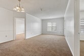 This single-story residence offers three bedrooms and two full bathrooms within a thoughtfully designed layout. A central hallway connects the main living areas, transitioning from hardwood-style flooring in the entry and kitchen zones to plush wall-to-wall carpeting throughout the bedrooms and living space. The galley-style kitchen is efficiently organized with rich dark espresso cabinetry, white countertops, a double stainless steel sink, electric range, refrigerator, and dishwasher — all lining both walls to maximize workspace. A dedicated utility area is accessible directly from the kitchen. The primary bedroom is a comfortable, well-proportioned space featuring a ceiling fan with light fixture, natural window light, and direct access to a private en-suite bathroom. The en-suite includes a wide vanity with dark cabinetry, a large mirror, and a tub/shower combination with white tile surround. The secondary bedrooms also feature ceiling fans and windows that bring in natural light. The second full bathroom mirrors the style of the first, complete with matching cabinetry, countertop, and a tiled tub/shower. Textured ceilings are consistent throughout, adding a classic residential character to the overall aesthetic.