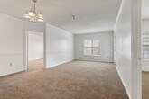 This single-story residence offers three bedrooms and two full bathrooms within a thoughtfully designed layout. A central hallway connects the main living areas, transitioning from hardwood-style flooring in the entry and kitchen zones to plush wall-to-wall carpeting throughout the bedrooms and living space. The galley-style kitchen is efficiently organized with rich dark espresso cabinetry, white countertops, a double stainless steel sink, electric range, refrigerator, and dishwasher — all lining both walls to maximize workspace. A dedicated utility area is accessible directly from the kitchen. The primary bedroom is a comfortable, well-proportioned space featuring a ceiling fan with light fixture, natural window light, and direct access to a private en-suite bathroom. The en-suite includes a wide vanity with dark cabinetry, a large mirror, and a tub/shower combination with white tile surround. The secondary bedrooms also feature ceiling fans and windows that bring in natural light. The second full bathroom mirrors the style of the first, complete with matching cabinetry, countertop, and a tiled tub/shower. Textured ceilings are consistent throughout, adding a classic residential character to the overall aesthetic.
