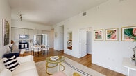 Located at 1625 NW 20th St in Miami, FL, this modern 2-bedroom, 2-bathroom residence offers a thoughtfully designed open-concept layout with clean lines and contemporary finishes throughout. Warm wood-look flooring flows seamlessly across the living, dining, and kitchen areas, creating a cohesive and inviting atmosphere. The living room is bright and airy, anchored by expansive floor-to-ceiling windows and corner glass panels that frame sweeping views of the Miami skyline and surrounding cityscape. The kitchen is sleek and well-appointed, featuring light wood cabinetry extending to the ceiling, white quartz countertops, stainless steel appliances including a French door refrigerator, dishwasher, and range, complemented by a bright window overlooking the city. A glass-top dining table with seating adds a stylish touch to the open dining area. Both bathrooms are finished with large-format tile, glass-enclosed walk-in showers, white vanities, and wood-look flooring. The primary bedroom is generously proportioned, boasting floor-to-ceiling sliding glass doors with direct access to a balcony and panoramic city views. A dedicated closet and in-unit laundry add everyday convenience. Hallways connect the spaces efficiently, rounding out this well-planned urban residence.