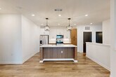 Located at 4101 Fiske Trail in Rockledge, Florida, this well-appointed 2-bedroom, 2-bathroom home offers a thoughtfully designed single-floor layout with a clean, contemporary aesthetic throughout. The open-concept living, dining, and kitchen area serves as the heart of the home, anchored by a striking kitchen island with a white quartz countertop, wood-toned cabinetry, and a matte black faucet. Stainless steel appliances, white upper cabinets, and two statement pendant lantern lights complete the modern kitchen design. Warm wood-look flooring flows seamlessly through the main living areas, complemented by recessed lighting and crisp white walls. The living area features large windows with natural light and a ceiling fan, along with built-in shelving for added functionality. The bedrooms are finished with plush carpeting and dark panel doors, offering a comfortable retreat. A well-organized walk-in closet with built-in shelving and drawers provides generous storage. The bathrooms are finished with wood-toned vanities, white countertops, and matte black hardware accents. A dedicated laundry room houses a full-size washer and dryer. A balcony extends the living space outdoors, rounding out this move-in-ready home.