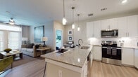 Located on W Broade Street in Leander, Texas, this single-story residence presents a thoughtfully designed open-concept layout with modern finishes throughout. Light-toned hardwood-style flooring runs continuously across the living spaces, contributing to a cohesive and airy aesthetic.

The kitchen serves as a central feature, outfitted with crisp white shaker cabinetry extending to the ceiling, granite countertops, a white subway tile backsplash, and a full suite of stainless steel appliances including a side-by-side refrigerator, electric range, and built-in microwave. A peninsula island with pendant lighting above provides bar seating and connects the kitchen seamlessly to the living area. A dedicated built-in desk nook adds functional workspace nearby.

The living room is well-proportioned, featuring a ceiling fan, neutral walls, and French doors that open to an outdoor area, allowing natural light to fill the space. The bedrooms are comfortably sized with large windows, hardwood-style flooring, and ample natural light from outdoor views.

The bathroom features a granite-topped vanity with white cabinetry, a tub-shower combination with white tile surround, and a walk-in closet with rod and shelf storage. The overall ambiance throughout is clean, contemporary, and welcoming.