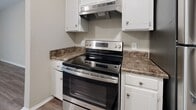 Located at 415 W Northfield Blvd in Murfreesboro, Tennessee, this single-floor residence offers a thoughtfully designed layout with a clean, neutral aesthetic throughout. The kitchen is equipped with stainless steel appliances, including an electric range with an overhead ventilation hood, complemented by white cabinetry with brushed nickel hardware and dark granite-style countertops — a practical and attractive workspace for cooking. The living areas feature warm wood-look luxury vinyl plank flooring that extends throughout the main spaces, creating a cohesive and easy-to-maintain environment. A louvered closet door adds a classic touch, while neutral wall tones keep the atmosphere bright and versatile. The bedrooms are finished with plush wall-to-wall carpeting and feature windows with blinds that allow natural light to filter in, offering views of surrounding greenery. Both bathrooms mirror the kitchen's design language, showcasing white cabinetry, dark granite-style countertops with undermount sinks, large mirrors, and tiled shower-tub combinations. Wood-look flooring ties the bathrooms together with the rest of the home. Overall, this residence presents a consistent, move-in-ready aesthetic with functional finishes and a comfortable, welcoming ambiance throughout.