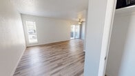 Located at 5900 Enterprise Ct in El Paso, TX, this single-story, 2-bedroom unit offers a practical and well-organized floor plan across a compact but efficiently utilized footprint. The layout includes a living room, two bedrooms, a kitchen, a hallway, and a closet, all connected in a straightforward arrangement.

The living room is a bright, open space featuring light wood-look luxury vinyl plank flooring that extends through the main living areas. A textured ceiling adds visual interest, while multiple windows fitted with horizontal blinds allow natural light to filter in. A sidelight panel beside the front entry door further enhances the brightness of the space.

The kitchen connects to the living area via a pass-through counter with white cabinetry and stone-look countertops, providing a functional workspace. The unit includes a full-size refrigerator and maintains consistent flooring throughout this area.

Both bedrooms are carpeted and painted in soft, neutral tones. Each room is equipped with a ceiling fan and light fixture, and windows with blinds provide natural light and privacy. The primary bedroom, slightly more compact in scale, features two windows for added ventilation and brightness.

A louvered utility closet door is visible near the living area, offering convenient storage access. Overall, the space presents a clean, neutral aesthetic suited for comfortable everyday living.