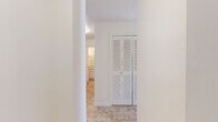 Located at 12017 Salon Drive in Orlando, Florida, this single-story home offers a clean, bright, and functional layout throughout. The interior is finished with neutral white walls and a consistent design language that creates a cohesive and airy atmosphere across all areas.

The bedrooms are carpeted in a neutral tone, providing a comfortable underfoot feel, and each room benefits from good natural light. One bedroom features a window overlooking the exterior, allowing sunlight to fill the space. The rooms offer a blank canvas well-suited for a variety of furniture arrangements.

The hallway and common areas are finished with durable stone-look tile flooring, which flows seamlessly between spaces. A standout feature of the hallway is a set of full-length louvered bi-fold closet doors, offering generous storage while maintaining the home's clean aesthetic. Structural column detailing in the hallway adds a subtle architectural element to the transitional spaces.

The bathroom is finished with white square wall tiles surrounding a full-sized soaking tub and shower combination. Matching tile flooring, a toilet, and classic fixtures complete the space in a tidy, functional manner.

The overall floorplan, visible in the dollhouse view, reflects a compact yet efficient layout with well-defined rooms and easy connectivity between living, sleeping, and bathing areas.