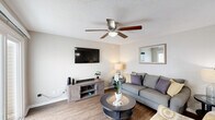 This two-story, three-bedroom, three-bathroom home in Charlotte, NC is thoughtfully laid out across two floors. The main level hosts the primary living and entertaining areas, including a bright living room with wood-look flooring, a ceiling fan, and a sliding glass door that opens to a private patio, filling the space with natural light. Adjacent to the living room, the dining area is anchored by an elegant chandelier and connects seamlessly to a galley-style kitchen featuring rich dark wood cabinetry, a white breakfast bar counter, and black appliances — all opening conveniently to the dining space through a pass-through window. The upper level accommodates the bedrooms, each equipped with ceiling fans and carpeted flooring. The spacious primary bedroom includes a walk-in closet and windows overlooking the surrounding area. The additional bedrooms offer ample natural light and closet space. Three bathrooms serve the home, featuring granite-topped vanities, large mirrors, and shower-tub combinations. Three dedicated closets and a hallway provide practical storage throughout. The neutral color palette and consistent finishes across both floors create a cohesive, comfortable atmosphere throughout this well-appointed Charlotte home.