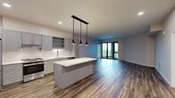 Located at 1850 Green Bay Rd in Highland Park, IL, this well-appointed one-bedroom, two-bathroom residence offers a thoughtfully designed single-floor layout with generous living space. The open-concept kitchen and living area is anchored by rich hardwood-style flooring and flows seamlessly toward floor-to-ceiling sliding glass doors that open to a private balcony with outdoor views, filling the space with natural light. The kitchen features gray shaker-style cabinetry with gold hardware, a marble-look tile backsplash, quartz countertops, and a full suite of stainless steel appliances including a gas range and refrigerator. The spacious bedroom is finished with plush carpeting and connects to a dedicated walk-in closet outfitted with custom shelving and hanging rods for ample storage. Both bathrooms are finished consistently with large-format white tile flooring, gray vanities with gold hardware, white countertops, and well-lit mirrors, lending a clean and modern aesthetic throughout. A dedicated laundry room with wood-style flooring and additional shelving adds everyday convenience. The neutral color palette, modern finishes, and abundant natural light create a bright, cohesive ambiance across the entire residence.