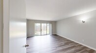 Located at 3209 Raleigh Dr in Toledo, OH, this two-story Philadelphia-style townhome offers a well-organized layout across two floors. The main level houses the living room, kitchen, and dedicated storage closets, while the upper level accommodates both bedrooms, a full bathroom, and additional closet space.

The living room is a standout space, featuring contemporary luxury vinyl plank flooring in a warm gray tone and large sliding glass doors that flood the room with natural light and provide direct access to a private outdoor patio area with wood fencing. The clean, neutral gray walls and crisp white trim create a bright, modern aesthetic throughout.

The kitchen is equipped with dark cabinetry, white countertops, and white appliances including a refrigerator and electric range. A generously sized window allows ample natural light and views of the surrounding greenery.

Upstairs, the spacious primary bedroom offers room to comfortably accommodate full furnishings, while the second bedroom features its own window with outdoor views. Both rooms continue the LVP flooring and neutral color palette found throughout the home. The full bathroom includes a tub-shower combo, toilet, and a vanity with under-sink storage. Three closets across the home provide practical and plentiful storage solutions.