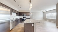 Located in Easley, South Carolina, this single-floor, one-bedroom, one-bathroom residence offers a thoughtfully designed layout that maximizes comfort and functionality. The open-concept kitchen and living area serves as the heart of the home, featuring rich dark cabinetry, granite countertops, a central island with pendant lighting overhead, and a full suite of stainless steel appliances including a side-by-side refrigerator with ice maker, dishwasher, microwave, and range. Light wood-look flooring flows throughout the main living areas, complementing the neutral warm-toned walls and creating a cohesive, modern aesthetic. A ceiling fan in the living area adds comfort and airflow to the space. The bedroom is carpeted for warmth and comfort, featuring a ceiling fan and a window that allows natural light to fill the room. The bathroom is clean and functional, offering a full tub-shower combination with white tile surround and chrome fixtures. A dedicated laundry room houses a full-size washer and dryer, providing added everyday convenience. Additional storage is available through a closet. Natural light is present throughout the residence via multiple windows dressed with blinds, contributing to a bright and inviting overall ambiance.