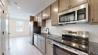 Located at 80 S. Sounders Ave in Columbus, OH, this thoughtfully designed single-floor unit makes excellent use of its compact footprint. The space includes a living room, kitchen, full bathroom, two closets, a laundry area, and a utility room—offering a complete and functional layout.

The kitchen is a standout feature, outfitted with warm-toned shaker-style cabinetry, dark granite countertops, a white subway tile backsplash, and a full suite of stainless steel appliances including a refrigerator, electric range, over-the-range microwave, and dishwasher. A matte black faucet with undermount sink adds a contemporary touch.

The living room is bright and open, with light-toned luxury vinyl plank flooring that runs throughout the entire unit. Natural light flows in through windows fitted with horizontal blinds, and recessed lighting provides clean, modern illumination overhead. Neutral white walls create a versatile canvas throughout.

The bathroom features granite countertops that mirror the kitchen's aesthetic, a wood-toned vanity with matte black hardware, and a full tub-shower combination with built-in shelving. The laundry area is conveniently accessible from the bathroom. Two closets provide practical storage solutions. The front entry includes a modern smart lock, adding a layer of security and convenience.