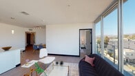 Located in the heart of Los Angeles at 525 N Wilton Place, this contemporary single-floor residence showcases sleek modern architecture defined by clean lines, crisp white walls, and warm wood-tone flooring throughout. The open-concept living and dining area is bathed in natural light courtesy of expansive floor-to-ceiling glass sliding doors that frame captivating views of the surrounding cityscape and Hollywood Hills beyond, while also providing seamless access to an outdoor balcony. The kitchen is thoughtfully designed with high-gloss white cabinetry, a generous quartz waterfall-edge peninsula with bar seating, stainless steel appliances, and stylish pendant lighting overhead. The bedrooms are bright and airy, each benefiting from large windows or glass doors that invite abundant natural light and offer scenic views of the hills and city streets below. The primary bedroom features a spacious walk-in closet with a modern sliding frosted-glass door and an en suite bathroom appointed with a soaking tub, tiled shower, and light wood flooring. A second full bathroom maintains the same clean, minimalist aesthetic. A well-curated hallway adorned with framed artwork connects the rooms, completing this polished and contemporary urban residence.