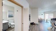 Located at 2555 Duportail St in Richland, WA, this one-bedroom, two-bathroom residence offers a thoughtfully organized single-level layout with clean, modern finishes throughout. The open living area features durable wood-style flooring, bright white walls, and a large sliding glass door that floods the space with natural light and provides views of the surrounding greenery. The adjoining dining area flows seamlessly from the living room, creating a cohesive and functional common space.

The kitchen is designed in a U-shaped configuration, featuring gray cabinetry with modern hardware, white countertops, a stainless steel sink, and a full suite of appliances including a range, dishwasher, and refrigerator. A skylight overhead adds additional brightness to the workspace.

The bedroom is a comfortable retreat with plush carpet flooring, its own sliding glass door with outdoor views, and direct access to a spacious walk-in closet equipped with a full hanging rod and shelving. Both bathrooms are finished with wood-style flooring, clean white vanities, and large mirrors. One bathroom includes accessibility-friendly grab bars for added convenience.

A dedicated entry hallway with a louvered closet door and coat hooks provides practical organization upon entry, completing this well-appointed home.