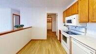 Located at 700 Douglas Avenue in Minneapolis, Minnesota, this one-bedroom, one-bathroom residence offers a practical and well-organized single-floor layout. The spacious living room is highlighted by a large sliding glass door that opens to a private balcony, flooding the space with natural light and offering sweeping views of the city and surrounding greenery. Plush carpet and baseboard heating throughout the living and sleeping areas add warmth and comfort. The kitchen features warm honey-toned wood cabinetry, white appliances including a range, built-in microwave, and refrigerator, along with light hardwood-style flooring and a peninsula that opens toward the living area. The generously sized bedroom includes a ceiling fan, a window with city views, baseboard heating, and mirrored sliding closet doors that enhance the sense of space. In total, three closets provide ample storage throughout the unit. The hallway connects the rooms efficiently, lined with additional built-in closet space. The bathroom is finished with white tile flooring and a wood-toned vanity. An in-unit laundry area adds everyday convenience. Textured ceilings and warm wood door trim carry a consistent aesthetic throughout the entire residence.