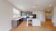 Located at 5375 Allatoona Gateway in Acworth, GA, this single-story, 3-bedroom, 2-bathroom home offers a well-designed layout with modern finishes. The open-concept kitchen is a standout feature, showcasing dark espresso cabinetry, light granite countertops, a central island with a white pedestal base, black appliances, and recessed lighting. A large window floods the kitchen with natural light, while light wood-style flooring extends into the adjacent living area, which also benefits from a ceiling fan and outdoor views. The three bedrooms are finished with plush neutral carpeting, ceiling fans, and windows that bring in ample natural light. One bedroom includes a built-in closet with shelving for convenient storage. The two bathrooms are clean and functional — one features a tub/shower combination with open shelving, dark vanity cabinetry, and granite countertops, while the other offers a walk-in shower with built-in corner shelving. A hallway connects the living spaces to the bedrooms, and a dedicated closet provides additional storage. The home's neutral color palette, consistent finishes, and practical layout create a cohesive and comfortable living environment.