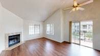 This well-appointed 2-bedroom, 2-bathroom single-story residence offers a thoughtfully arranged floor plan that maximizes functionality and comfort. The living room serves as the centerpiece of the home, featuring striking vaulted ceilings, rich hardwood-style flooring, a stone-surround fireplace, and multiple windows that flood the space with natural light. A ceiling fan adds practicality, while sliding glass doors provide direct access to an outdoor deck, extending the living area outdoors. The kitchen is efficiently designed with warm wood cabinetry, ample counter space, a full suite of white appliances, and a window above the sink that brings in additional natural light. A secondary door offers convenient exterior access. Both bedrooms are carpeted and benefit from vaulted ceilings and ceiling fans, creating an airy feel. The primary bedroom includes a mirrored sliding-door closet with built-in shelving and hanging rods. The two bathrooms are finished consistently, each featuring wood-toned vanity cabinetry, light countertops, and hardwood-style flooring. One bathroom includes a window for natural ventilation, while both offer large mirrors above the vanities. Three hallways connect the rooms, and a dedicated closet provides additional storage throughout this cohesive and practical home.