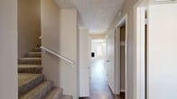 This two-story home in El Paso's 79912 zip code offers a well-organized layout across two floors, providing comfortable living spaces throughout. The main level features an open kitchen and living area, where the kitchen stands out with rich dark cabinetry, mosaic tile backsplash, stainless steel appliances, light countertops, a skylight detail above, and wood-look flooring that flows seamlessly through the home.

The living room is bright and airy, bathed in natural light with clean neutral walls and the same wood-look flooring. The generously sized primary bedroom includes a ceiling fan, mirrored closet doors, and sliding glass doors that open to a private outdoor patio framed by a natural stone wall. Additional bedrooms are well-proportioned, each featuring ceiling fans, natural light from windows, and dedicated closet space — including walk-in closets with built-in shelving.

The four bathrooms are clean and functional, featuring wood-look tile flooring, tub-shower combinations, and vanities with dark cabinetry and framed mirrors. Hallways are well-connected, with carpeted stairs leading to the upper floor. Textured ceilings are present throughout, adding a classic touch to the home's overall warm and neutral aesthetic.