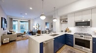 Located at 8011 Old Georgetown Rd in Bethesda, MD, this well-appointed 2-bedroom, 2-bathroom residence offers a thoughtfully designed single-level layout. The open-concept kitchen and living area serves as the heart of the home, showcasing bold navy lower cabinetry paired with crisp white upper cabinets, a quartz waterfall island with seating, and polished globe pendant lights in brushed nickel. A decorative geometric tile backsplash and stainless steel appliances complete the kitchen. The living room flows naturally from the kitchen and is bathed in natural light through large floor-to-ceiling windows, with warm hardwood flooring tying the spaces together. The primary bedroom is a serene retreat featuring plush carpet, a ceiling fan, and expansive windows overlooking the outdoors. Both bedrooms are complemented by dedicated walk-in closets with built-in shelving and hanging systems. The two bathrooms are finished with marble-style tile flooring, sage-toned shaker vanities, quartz countertops, and glass-enclosed showers. One bathroom includes a dual-sink vanity with a large mirror, offering added convenience. The overall aesthetic is clean, contemporary, and refined throughout.