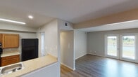 This single-floor residence is designed with a practical, open layout that connects the main living and kitchen areas seamlessly. The kitchen is equipped with warm wood-toned cabinetry, black appliances including a gas range and refrigerator, recessed lighting, and a peninsula countertop with a double-basin sink that opens toward the living space—ideal for both everyday use and entertaining. The spacious living area benefits from natural light streaming through a set of double French doors, which offer outdoor views and contribute to an airy, welcoming atmosphere.

Wood-style hard-surface flooring runs consistently throughout the unit, providing a cohesive and easy-to-maintain finish. The bedrooms are generously proportioned, with one featuring a double-door closet and a ceiling light fixture, while another offers a bright window with outdoor views. Additional storage is accessible via closets positioned off the main corridor.

The bathroom is thoughtfully designed with accessibility in mind, featuring grab bars, a wall-mounted sink with exposed plumbing, a mirrored medicine cabinet, and a three-bulb vanity light. Neutral wall tones throughout the unit create a clean, understated palette that adapts well to a variety of décor styles.