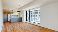 Located at 600 Mountaineer Private in Ottawa, this contemporary one-bedroom, one-bathroom unit offers a well-designed single-floor layout with thoughtful use of space throughout. Light hardwood flooring flows seamlessly across all living areas, complementing the clean white walls and modern finishes that define the overall aesthetic.

The open-concept living, dining, and kitchen area serves as the heart of the unit. Large floor-to-ceiling sliding windows and a full-width glazed door flood the space with natural light while offering urban views. The kitchen is a standout, featuring a sleek island with a white quartz countertop and integrated sink, stainless steel appliances including a full-size refrigerator and range, grey cabinetry, a subway tile backsplash, and stylish pendant lighting overhead.

The bedroom is a bright, well-proportioned retreat with a large window drawing in natural light. A versatile den provides additional functional space, ideal for a home office. Two closets offer ample storage throughout the unit. The bathroom is finished with large-format grey tile flooring, a glass-enclosed walk-in shower, and recessed lighting. A dedicated laundry room and utility room add everyday convenience. The hallway connects all spaces efficiently, completing this polished and functional urban home.