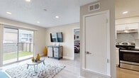 This efficiently designed single-floor unit offers a thoughtful layout across one bedroom and two bathrooms, making excellent use of its compact footprint. The living room serves as the heart of the space, featuring light wood-style flooring, recessed lighting, a textured ceiling, and a wall-mounted TV. A sliding glass door floods the room with natural light and opens directly to a private outdoor patio with a grassy area, creating a seamless indoor-outdoor connection.

Adjacent to the living room, the dining area accommodates a full-sized table and chairs beneath a pendant light fixture, with a window dressed in bold navy curtains adding a pop of color. The galley-style kitchen is well-equipped with stainless steel appliances, including a range and refrigerator, white cabinetry, clean white countertops, and a decorative tile backsplash.

The bedroom is carpeted and comfortably sized, featuring a ceiling fan, a window with natural light, and neutral walls that create a calm, restful atmosphere. A hallway leads to the bathrooms, one of which includes a white vanity with a well-lit mirror, providing a clean and functional space. A dedicated closet completes the unit, offering practical storage throughout.