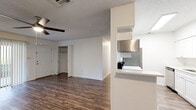 Located at 2701 NW 23rd Blvd in Gainesville, FL, this single-floor unit offers a clean, functional layout designed for comfortable everyday living. The open living area is finished with durable wood-style flooring and features a ceiling fan with integrated lighting, white walls, and a textured ceiling. Built-in shelving and a walk-in closet add practical storage directly off the main living space.

The galley-style kitchen is well-appointed with white shaker cabinetry, light quartz countertops, a stainless steel refrigerator, microwave, electric range, and dishwasher. A pass-through counter connects the kitchen to the living area, enhancing the sense of openness. A dedicated in-unit laundry area accommodates a full-size washer and dryer.

The bedroom is carpeted for comfort and includes a ceiling fan, a large window that invites natural light and outdoor views, and a closet with ample storage. The bathroom is finished in crisp white tones, featuring a single-sink vanity with a quartz countertop, a full tub-shower combination, and wood-style flooring that ties the space together cohesively.

Throughout the unit, the consistent use of neutral tones and practical finishes creates a bright, clean atmosphere suited for a variety of lifestyles.