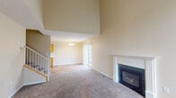 Located at 811 Tenth Ave N in Sartell, Minnesota, this two-story home offers a well-organized layout across two levels connected by a staircase with a white-railed banister. The main living area is immediately striking, featuring dramatically vaulted ceilings that create an expansive, open atmosphere. A gas fireplace with a decorative white mantel and dark tile surround serves as a focal point, while large sliding glass doors and windows allow natural light to fill the space. Neutral-toned carpet throughout the living area adds warmth underfoot.

Adjacent to the living space, the galley-style kitchen is practical and well-equipped, featuring warm oak cabinetry extending to the ceiling for generous storage, white appliances, a double sink, light countertops, and durable wood-look flooring. A chandelier in the adjoining dining area adds a refined touch, with a sliding door providing direct outdoor access.

The bedrooms are carpeted and include built-in closets with bifold doors and wire shelving for organized storage. A bathroom with tile flooring serves the upper level. Additional utility is provided by a dedicated laundry area with tile flooring, conveniently situated near the upper-level hallway overlooking the main living space below.
