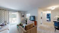 This single-level unit offers a practical and comfortable layout across one bedroom and one bathroom. The open-concept living room is carpeted and bathed in natural light from a sliding glass door that leads to a private outdoor balcony, ideal for casual outdoor seating. The living area provides ample room for a full seating arrangement and entertainment setup, with neutral walls and a soft color palette throughout.

The kitchen is efficiently designed with white shaker cabinetry, granite-style countertops, wood-look flooring, and stainless steel appliances including a gas range, dishwasher, and refrigerator. In-unit washer and dryer access is also present. The kitchen opens toward a dedicated dining area, creating a functional flow between meal preparation and dining.

The bedroom is generously proportioned, accommodating a queen or king bed alongside additional furniture, with carpeting, a wall-mounted HVAC unit, and windows that admit natural light. The full bathroom features a combined tub and shower, a white vanity, wood-look flooring, and a window for ventilation. Overall, the unit maintains a clean, cohesive aesthetic with a neutral tone throughout.