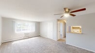 Located at 6951 York Rd in Parma Heights, Ohio, this two-bedroom, one-bathroom unit offers a practical and efficiently designed single-floor layout. The combined living and dining area serves as the heart of the home, featuring plush wall-to-wall carpeting, a ceiling fan with light fixture, and a large window dressed with vertical blinds that floods the space with natural light. A wall-mounted air conditioning unit and baseboard heating provide year-round comfort. The kitchen connects seamlessly to the living area via a pass-through counter, offering a functional workspace for everyday cooking. A hallway leads to the two carpeted bedrooms, each equipped with windows that bring in additional natural light and views of the surrounding neighborhood. The primary bedroom is generously sized, while the second bedroom offers comfortable accommodations as well. Four closets throughout the unit provide exceptional storage capacity, including a spacious walk-in closet with dual wire shelving. The full bathroom features a tiled tub and shower combo, pedestal sink, mirrored medicine cabinet, and warm hardwood flooring, maintaining a clean, bright aesthetic throughout. The overall ambiance is light, neutral, and move-in ready.