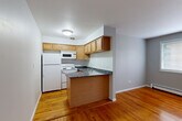 Located at 6040 N Sheridan Road in Chicago's Edgewater neighborhood, this single-floor unit offers an efficient and well-organized layout. Warm-toned hardwood floors run throughout the space, lending a cohesive and inviting feel to every room.

The combined living and dining area is open and practical, featuring soft gray walls and a window that allows natural light to filter in. A window air conditioning unit and baseboard heating provide year-round climate control. Two closets off the hallway offer ample storage for a space of this size.

The kitchen is a functional standout, featuring warm wood cabinetry that extends to the ceiling for maximum storage, dark granite countertops with subtle veining, a peninsula that opens toward the living area, a double stainless steel sink, and white appliances including a refrigerator, electric range, and built-in microwave.

The bathroom is clean and well-appointed, with white square tile in the shower/tub surround, classic mosaic tile flooring, a wood vanity with storage, and a full bathtub. A hallway connects all rooms, keeping the layout organized and easy to navigate. This unit provides a practical and comfortable living environment in a prime Chicago lakeside neighborhood.