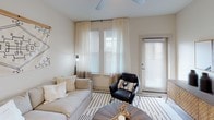 This single-story residence showcases a thoughtfully designed layout with a neutral color palette and modern finishes throughout. The kitchen serves as a central gathering space, featuring granite countertops, a large island with an undermount sink and seating, white upper cabinetry with glass-front accents, wood-toned lower cabinets, a subway tile backsplash, and a full suite of stainless steel appliances. Light wood-style flooring flows through the kitchen and connects seamlessly to adjoining areas.

The living room offers a bright and airy atmosphere, with multiple windows dressed in sheer curtains and blinds that invite abundant natural light. A ceiling fan adds comfort overhead, while direct access to an exterior door enhances the space's openness.

Multiple bedrooms are carpeted and well-appointed, each featuring ceiling fans, large windows with blinds and curtains, and generous natural light. The primary bedroom connects to a spacious en suite bathroom finished with granite countertops, wood-toned cabinetry, open shelving, a glass-enclosed shower, and direct access to a walk-in closet. A secondary bathroom mirrors the refined finishes with granite counters and wood-look flooring, maintaining a consistent, cohesive aesthetic throughout the residence.
