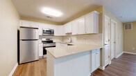 Located at 8894 Alleghany Rd in Corfu, NY, this single-floor residence offers a well-organized and efficiently designed layout across two bedrooms and multiple living spaces. The open-concept kitchen and living area serves as the heart of the home, featuring crisp white shaker-style cabinetry, light quartz countertops, a marble-look tile backsplash, and stainless steel appliances including a refrigerator, range, and built-in microwave. A peninsula counter provides additional prep space and creates a natural division between the kitchen and the adjacent living and dining areas. Warm-toned luxury vinyl plank flooring flows throughout the main living spaces, lending a clean and cohesive look. A dedicated pantry offers convenient storage directly off the kitchen. The bedrooms are carpeted for comfort and receive natural light through double-hung windows with views of the surrounding greenery. The primary bedroom provides a comfortable and well-proportioned retreat. Three closets throughout the unit offer ample storage. A family room adds further flexibility to the floor plan. Neutral wall tones, white trim, and consistent finishes throughout create a bright, move-in-ready atmosphere suited for a variety of living arrangements.