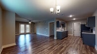 This single-story home offers a thoughtfully designed open-concept layout that seamlessly connects the living area and kitchen, creating a spacious and functional environment. Rich, dark hardwood-style flooring flows throughout the main living spaces, complemented by neutral gray-toned walls that lend a clean, contemporary feel.

The kitchen is a standout feature, equipped with gray shaker-style cabinetry, granite countertops, a classic white subway tile backsplash, and a full suite of stainless steel appliances including a range, microwave, dishwasher, and refrigerator. A kitchen island with a sink adds additional prep space and storage. The open living area benefits from a ceiling fan and a decorative chandelier, while double doors provide access to the exterior, allowing natural light to fill the space.

The bedrooms are carpeted for comfort and include ceiling fans and window blinds, offering a quiet, restful atmosphere. The bathroom is well-appointed with a granite-topped vanity, navy cabinetry, tile-surround soaking tub, and hardwood-style flooring, creating a refined and relaxing space. Throughout the home, clean lines, consistent finishes, and practical design choices contribute to an inviting and move-in-ready atmosphere.