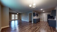 This single-story home offers a thoughtfully designed open-concept layout that seamlessly connects the living area and kitchen, creating a spacious and functional environment. Rich, dark hardwood-style flooring flows throughout the main living spaces, complemented by neutral gray-toned walls that lend a clean, contemporary feel.

The kitchen is a standout feature, equipped with gray shaker-style cabinetry, granite countertops, a classic white subway tile backsplash, and a full suite of stainless steel appliances including a range, microwave, dishwasher, and refrigerator. A kitchen island with a sink adds additional prep space and storage. The open living area benefits from a ceiling fan and a decorative chandelier, while double doors provide access to the exterior, allowing natural light to fill the space.

The bedrooms are carpeted for comfort and include ceiling fans and window blinds, offering a quiet, restful atmosphere. The bathroom is well-appointed with a granite-topped vanity, navy cabinetry, tile-surround soaking tub, and hardwood-style flooring, creating a refined and relaxing space. Throughout the home, clean lines, consistent finishes, and practical design choices contribute to an inviting and move-in-ready atmosphere.