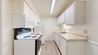 This single-floor, one-bedroom, one-bathroom residence in Saginaw, Michigan offers a well-organized layout designed for comfortable, everyday living. The galley-style kitchen is efficiently appointed with white cabinetry spanning both walls, providing generous upper and lower storage. Light-toned countertops, a double-basin sink, a full suite of white appliances including a range, microwave, refrigerator, and dishwasher, and durable wood-look flooring complete the kitchen's clean, functional aesthetic. The living area features plush carpeting and a large sliding glass door fitted with vertical blinds, allowing natural light to fill the room while offering access to an outdoor view. The bedroom is carpeted and includes a mirrored sliding-door closet for convenient storage, along with a window that brings in additional natural light. A secondary hallway closet provides further organizational space just outside the bedroom. The full bathroom features a single-vanity sink with a large mirror, a shower-tub combination, and a neutral color palette that contributes to a clean, understated finish throughout. The overall design of the unit emphasizes simplicity and practicality, with a consistent light and neutral tone carried across all rooms.