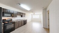 Located at 448 W Georgia St in Tallahassee, FL, this one-bedroom, one-bathroom unit offers a well-designed, single-floor layout that maximizes every square foot. The open-concept kitchen flows directly into the living area, creating a bright and connected space. The kitchen is outfitted with dark wood-tone cabinetry, granite-style countertops, a classic white subway tile backsplash, and a full suite of black appliances including a refrigerator, range, microwave, and dishwasher. Light wood-style flooring runs throughout the main living areas, complementing the crisp white walls and adding a clean, contemporary feel. The living area benefits from natural light through a window fitted with blinds, and a ceiling fan overhead provides comfortable airflow. The spacious bedroom continues the light flooring theme and includes its own ceiling fan, a window for natural light, and a dedicated closet with built-in shelving for ample storage. The bathroom features tile flooring, a vanity with granite-style countertop, and a full tub-shower combination with white tile surround. Louvered interior doors and neutral tones throughout lend the space a cohesive, modern aesthetic ideal for comfortable everyday living.