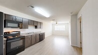 Located at 448 W Georgia St in Tallahassee, FL, this one-bedroom, one-bathroom unit offers a well-designed, single-floor layout that maximizes every square foot. The open-concept kitchen flows directly into the living area, creating a bright and connected space. The kitchen is outfitted with dark wood-tone cabinetry, granite-style countertops, a classic white subway tile backsplash, and a full suite of black appliances including a refrigerator, range, microwave, and dishwasher. Light wood-style flooring runs throughout the main living areas, complementing the crisp white walls and adding a clean, contemporary feel. The living area benefits from natural light through a window fitted with blinds, and a ceiling fan overhead provides comfortable airflow. The spacious bedroom continues the light flooring theme and includes its own ceiling fan, a window for natural light, and a dedicated closet with built-in shelving for ample storage. The bathroom features tile flooring, a vanity with granite-style countertop, and a full tub-shower combination with white tile surround. Louvered interior doors and neutral tones throughout lend the space a cohesive, modern aesthetic ideal for comfortable everyday living.