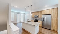 Located at 6519 Kings Glen Drive in Humble, TX, this two-story home offers a thoughtfully designed layout across two floors. The main level features an open-concept living and kitchen area with warm wood-look flooring and an abundance of natural light from large windows with white blinds. The kitchen is a standout, boasting a central island with a granite countertop and an undermount sink, complemented by light wood cabinetry, a gray tile backsplash, and a full suite of stainless steel appliances including a side-by-side refrigerator with ice maker, electric range, and over-the-range microwave. A half bathroom on the main floor adds convenience. Upstairs, the spacious primary bedroom features a ceiling fan, wood-look flooring, and access to a walk-in closet with built-in shelving. The bedroom is bathed in natural light through a bank of windows. The full upstairs bathroom is well-appointed with a soaking tub and shower combination featuring large-format tile surround, granite vanity countertop, light wood cabinetry, and brushed nickel fixtures. Clean white walls and consistent wood-look flooring throughout the home create a cohesive, modern aesthetic.