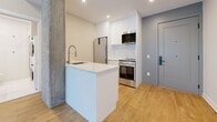 Located at 742 Rue William in Montreal's vibrant Griffintown neighbourhood, this well-appointed one-bedroom, one-bathroom unit offers a thoughtfully designed layout across a single floor. The open-concept kitchen is a standout feature, showcasing sleek white cabinetry, quartz countertops, a waterfall-edge island with an undermount sink, and a full suite of stainless steel appliances including a gas range, built-in microwave, and French door refrigerator. Exposed concrete columns add an industrial character that contrasts elegantly with the clean, modern aesthetic throughout. Warm-toned hardwood flooring runs continuously through the main living area, kitchen, and bedroom, lending a cohesive and inviting feel to the space. The bedroom is a serene and efficiently sized retreat, benefiting from a large window that draws in natural light. The bathroom is finished to a high standard, featuring large-format marble-effect floor and wall tiles, a floating white vanity with a mirrored medicine cabinet, a glass-enclosed shower, and the added convenience of an in-unit stacked washer and dryer. Recessed lighting throughout ensures a bright, well-lit environment. This unit combines urban industrial charm with refined modern finishes in one of Montreal's most dynamic neighbourhoods.