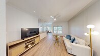 This thoughtfully designed 2-bedroom, 2-bathroom residence offers a seamless open-concept layout that connects the living, dining, and kitchen areas into one cohesive and functional space. Light-toned hardwood-style flooring runs throughout, complementing the crisp white walls and creating a bright, airy atmosphere. The living area features a ceiling fan, recessed lighting, and a clear sightline to the dining space and beyond, where large windows frame outdoor greenery views.

The kitchen is well-equipped with dark espresso cabinetry accented by gold hardware, granite countertops, stainless steel appliances, a double-basin sink, and stylish pendant lighting — combining both form and function. Adjacent to the kitchen, the dining area is illuminated by an elegant gold-and-white pendant light and benefits from a window overlooking a lush outdoor setting.

Both bedrooms are comfortable and well-lit, with ceiling fans and windows providing natural light. The bathrooms are cleanly finished, with one featuring a full tub-shower combination, wainscoting-style wall panels, and a modern vanity. A dedicated in-unit laundry room includes a full-size washer and dryer. The hallways are bright and efficiently designed, ensuring smooth flow throughout the residence.