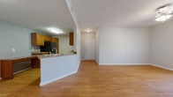 This thoughtfully designed one-bedroom, one-bathroom residence offers a comfortable and functional layout across a single floor. The open-concept living and kitchen area serves as the heart of the home, featuring warm hardwood-style flooring that flows throughout the main spaces. The kitchen is equipped with honey-toned wood cabinetry, granite-style countertops, black appliances including a refrigerator, electric range, and built-in microwave, along with a peninsula that provides additional prep space and a natural divide between the kitchen and living area. The living room receives natural light through a set of glass French doors, adding an airy, welcoming feel to the space. A ceiling fan with a light fixture adds both comfort and function. The bedroom is carpeted for warmth and comfort, featuring a ceiling fan, a window with outdoor views of lush greenery, and access to a spacious walk-in closet outfitted with wire shelving systems for ample storage. The bathroom is well-appointed with rich cherry-toned wood cabinetry, a granite-style vanity countertop, a large mirror, and hardwood-style flooring. A hallway connects the private and shared spaces, completing this efficiently organized and move-in-ready residence.