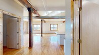 Located at 225 E 2nd St in downtown Davenport, Iowa, this 3-bedroom, 2-bathroom loft showcases a striking blend of historic industrial character and modern updates across a single, generously sized floor. The open-concept living and kitchen area is anchored by original hardwood floors, bold exposed timber columns and beams, and industrial-style ductwork that pays homage to the building's heritage. Multiple windows flood the space with natural light and frame captivating views of the waterfront. The kitchen features white shaker cabinetry, granite countertops and backsplash, stainless steel appliances, and a large island — all complemented by the rustic warmth of the surrounding hardwood floors and timber accents. The bedrooms offer a mix of exposed brick accent walls, hardwood flooring, and windows with views of the river and surrounding cityscape. The spacious primary bedroom provides ample room to relax. The bathrooms are finished with neutral tile flooring, clean white vanities, and modern fixtures. Throughout the space, the combination of whitewashed and natural brick walls, warm wood tones, and soaring ceilings creates an inviting industrial-chic ambiance unique to this downtown riverfront location.