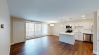 Located at 12225 Huffman Rd in Parma Heights, Ohio, this single-floor residence offers a thoughtfully designed open-concept layout that seamlessly connects the living area and kitchen. Rich hardwood flooring extends throughout the main living space, complemented by neutral-toned walls that create a bright and welcoming atmosphere. A large bank of floor-to-ceiling vertical blinds in the living area allows for generous natural light and outdoor views, enhancing the sense of openness.

The kitchen is a standout feature, outfitted with crisp white shaker-style cabinetry, light quartz countertops, a classic subway tile backsplash, and a full suite of stainless steel appliances including a range, microwave, dishwasher, and refrigerator. A central island with pendant lighting above provides additional prep and seating space, while recessed and pendant lighting throughout ensures the kitchen is well-lit.

The bedrooms are finished with plush carpeting and warm beige walls, offering a comfortable and quiet retreat. Windows with horizontal blinds allow for natural light while maintaining privacy. The bathroom features a clean, modern design with a soaking tub and shower combination, neutral tile surround, a white vanity with an integrated sink, and an illuminated mirror, all finished in a cohesive, contemporary style.