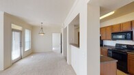 This single-floor, 1-bedroom, 1-bathroom residence features a thoughtfully arranged layout that maximizes functionality. The living area is bright and open, benefiting from large arched windows that allow abundant natural light to fill the carpeted space. A pendant light fixture adds a decorative touch, while a glass-paneled entry door further enhances the sense of openness. The pass-through counter connecting the kitchen to the living area promotes an integrated flow between the two spaces.

The galley-style kitchen is well-equipped with warm-toned wood cabinetry extending to the upper walls, dark granite-style countertops, tile flooring, and black appliances including a refrigerator, electric range, built-in microwave, and dishwasher. Ample counter and storage space make this kitchen highly practical.

The bedroom features plush carpeting, a ceiling fan with light, and a prominent arched window that invites natural light and provides an airy feel. The full bathroom includes tile flooring, a single-sink vanity with wood cabinetry, overhead storage cabinets, and a full-size soaking tub with shower combination, offering a clean and functional design throughout.