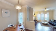 This thoughtfully designed 1-bedroom, 1-bathroom floor plan offers a seamless single-level layout that balances comfort and functionality. Rich hardwood flooring flows throughout the main living areas, complemented by crown molding and warm neutral tones that lend an inviting atmosphere. The kitchen is well-equipped with dark espresso cabinetry, granite countertops, a subway tile backsplash, and a full suite of stainless steel appliances, including a refrigerator with ice maker, electric range, and built-in microwave. A peninsula provides additional counter space and a natural transition into the dining area, where a pendant light fixture illuminates the space. The living room features multiple windows dressed with sheer curtains and plantation shutters, filling the room with natural light, and is finished with a ceiling fan overhead. The bedroom offers plush carpeting, a ceiling fan, and a sliding glass door that opens to an outdoor view. The bathroom includes dark cabinetry with ample storage, a soaking tub with shower, and a large vanity mirror. A dedicated laundry closet with a full-size washer and dryer is conveniently located within the unit, adding a practical finishing touch to this well-rounded home.