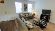 This thoughtfully designed residence spans three floors, offering a generous and versatile layout suited for a variety of lifestyles. The living area serves as a welcoming centerpiece of the home, featuring a bright and open arrangement filled with natural light streaming through multiple windows. The space accommodates ample seating, making it ideal for both relaxing and entertaining. Durable hardwood-style flooring transitions seamlessly into plush carpeting, adding warmth and comfort underfoot. Neutral-toned walls provide a clean, timeless backdrop that complements a wide range of furnishing styles. The windows offer views of the surrounding exterior, enhancing the sense of openness throughout. The multi-floor configuration allows for a natural separation of living, sleeping, and utility spaces, contributing to an organized and private atmosphere within the home. Each level is designed to serve a distinct purpose, supporting both communal and private living. The overall ambiance is warm and inviting, with a practical layout that balances functionality with comfort. Clean architectural lines and well-proportioned rooms give the space a polished, move-in-ready feel throughout all three floors.