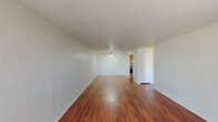 This 690 square foot apartment, located in Summit West - 17B - A1, offers a thoughtfully designed living space. The single-story layout comprises one bedroom, one bathroom, and an open-concept living area. The primary bedroom, measuring 160 square feet, provides ample space and features plush carpeting and a built-in closet.

The apartment showcases a blend of flooring materials, with rich wood flooring in the main living areas and kitchen, creating a warm and inviting atmosphere. Large windows throughout allow for abundant natural light, enhancing the sense of space. The living room is spacious, with room for both seating and dining areas.

The kitchen, while compact, is efficiently designed with wooden cabinetry, a full-sized refrigerator, and ample counter space. A convenient in-unit laundry area adds to the apartment's practicality. The bathroom features a standard tub-shower combination with white tiling for easy maintenance.

Additional storage solutions include a dedicated closet space with wire shelving. The apartment also benefits from modern amenities such as central air conditioning, as evidenced by the ceiling vents. Overall, this apartment offers a comfortable and functional living space, ideal for singles or couples seeking a well-appointed home in a convenient location.