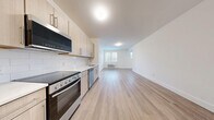 Located at 11 1st Ave in Bay Shore, NY, this thoughtfully designed 2-bedroom, 1-bathroom unit offers a clean, modern aesthetic across a single floor. Light wood-look flooring runs continuously throughout the space, complementing the bright white walls and creating a warm, cohesive feel.

The kitchen is outfitted with light wood cabinetry, a white subway tile backsplash, and a full suite of stainless steel appliances including a refrigerator, range with oven, built-in microwave, and dishwasher. It opens directly into a generous living area with a window that allows natural light to flow into the space.

The primary bedroom is spaciously sized, featuring a triple window arrangement that bathes the room in natural light, while the second bedroom also includes a window with exterior views and direct access to a closet. Both rooms offer comfortable proportions and a clean, neutral palette. A dedicated closet area provides additional storage.

The bathroom is finished with large-format white subway tile in the tub and shower surround, paired with a floating wood vanity and light tile flooring for a polished, contemporary look. A separate utility area houses a stacked washer and dryer alongside a water heater, adding everyday convenience to this well-appointed unit.